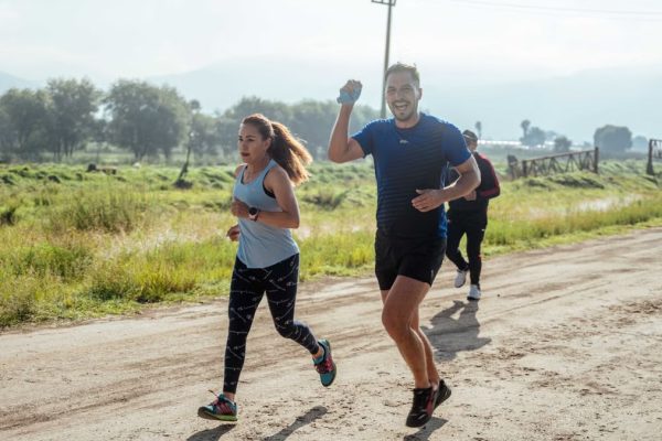 A group of runners enjoys a vibrant morning jog on a rural dirt road.